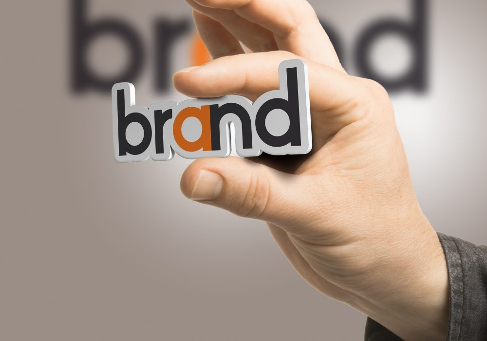 One hand holding the word brand over a beige background. Branding concept. The image is a composition between 2D illustration, 3D rendering and photography